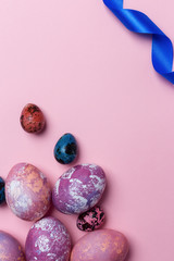 Holiday Easter eggs with white and blue ribbon on pink background