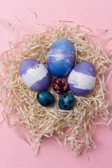 Close up Easter eggs in nest with white ribbon on pink background. Easter texture