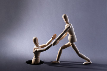 People helping another. People helping each other. Wooden mannequin. Wooden man helps another.