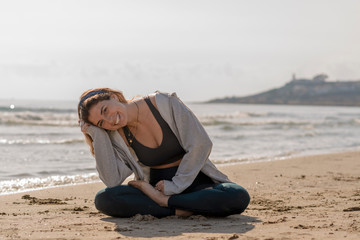 beautiful woman doing yoga and meditating on the seashore