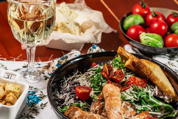 Caesar salad with salmon. Served with white wine. Salad with red fish fillet, cesar sauce, croutons, lettuce, cherry tomato, close up.