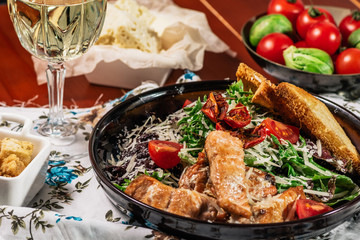 Caesar salad with salmon. Served with white wine. Salad with red fish fillet, cesar sauce, croutons, lettuce, cherry tomato, close up.