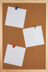 Fototapeta premium Cork board with pinned colored pins and white note sheets