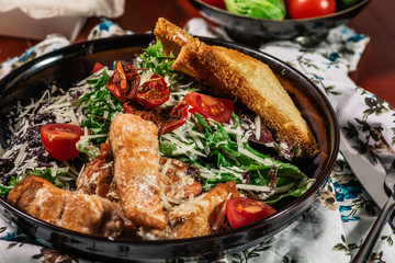 Caesar salad with salmon. Served with white wine. Salad with red fish fillet, cesar sauce, croutons, lettuce, cherry tomato, close up.