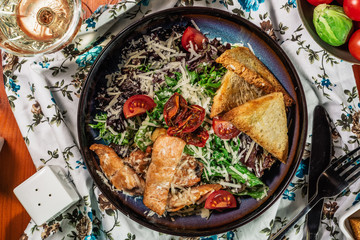 Cesar salad. Salad with marinated salmon, eggs, parmesan and tomatoes. Served with white wine. top view.