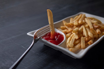 Plate of golden French fries, potato chips, or Pommes Frites, close-up with barbecue sauce