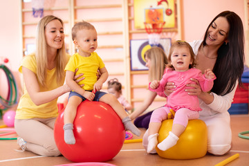 Mothers with babies doing exercises with gymnastic ball in gym. Concept of caring for the child's...