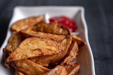 A plate with fried golden potatoes in country style with tomato sauce