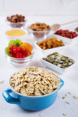 Oat flakes in blue bowl and various delicious ingredients for healthy breakfast on the kitchen table. Healthy breakfast concept.