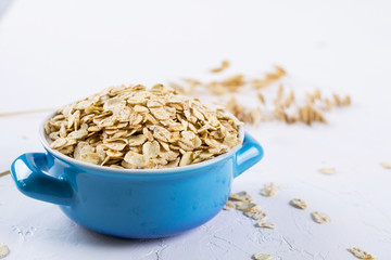 Oat flakes in blue bowl on the kitchen table. Healthy breakfast concept.