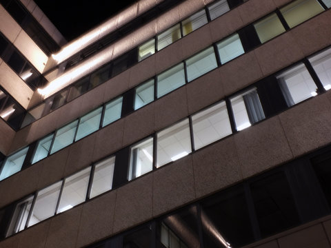 the corner of an office building at night with illuminated walls and lights shining on the exterior facade