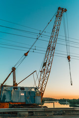 Fototapeta premium Soviet crane on city bridge at sunrise