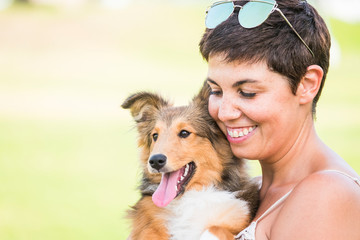 Portrait of cute pretty cheerful girl with young puppy shetland dog together in love and friendship...
