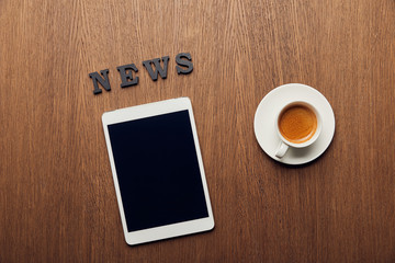 top view of digital tablet with blank screen near news lettering and cup of coffee