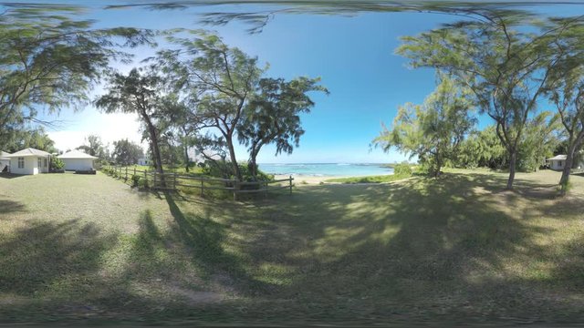 360 VR video. Small guest houses among green trees opening onto the beach and blue ocean. Mauritius scene on bright sunny day