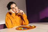 Smiling artistic woman choosing paint color on a palette