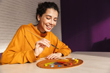 Smiling artistic woman choosing paint color on a palette