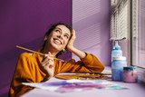 Smiling artistic woman choosing paint color on a palette
