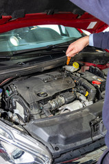 Technician checking the oil level of a car in a inspection workshop