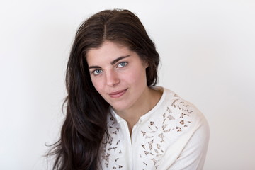 Obraz premium Medium horizontal shot of beautiful young brunette girl wearing vintage white embroidered sweater with hair cascading on right shoulder staring