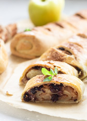 Traditional apple strudel with raisin and cinnamon on grey concrete background. Copy space.