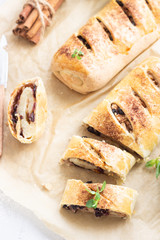 Traditional apple strudel with raisin and cinnamon on grey concrete background. Copy space.