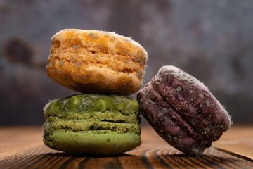 3 pcs moldy macaroons on a wood table close up