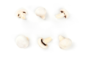 Champignon mushrooms, whole and sliced, shot from above on a white background, forming a frame with copy space