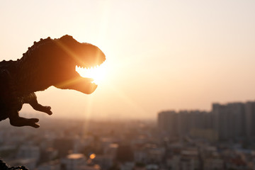 Fototapeta premium silhouette of tyrannosaurus and buildings in sunset time