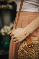 Obraz na płótnie Canvas Fashionable young blogger girl holding a circle straw bag, wearing a handmade bracelet. Concept of blogging and street style fashion. Summer and spring outfit ideas.