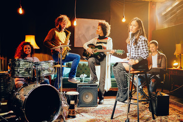 Band practice in home studio. Woman singing while rest of the band playing instruments.