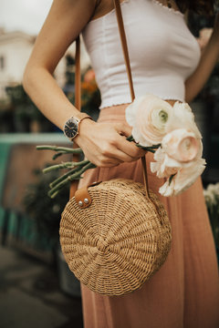 Fashionable young blogger girl holding a bunch of flowers at the flower market. Concept of blogging and street style fashion. Summer and spring outfit ideas.