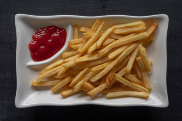Plate of golden French fries, potato chips, or Pommes Frites, close-up with barbecue sauce