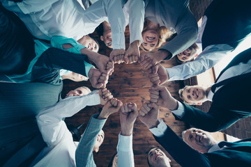 Close up low angle view photo diversity members business people circle she her he him his hold hands arms fists together celebrate project nomination power inspiration formal wear jackets shirts