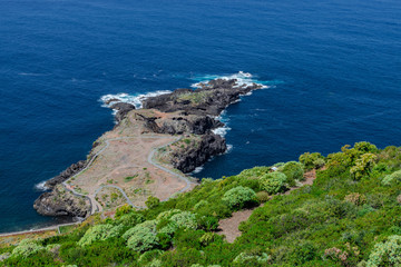 Fototapeta na wymiar El Sauzal volcanic coastline, stone path and green vegetation, with blue Atlantic ocean, Tenerife, Canary islands, Spain