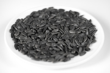 Black sunflower seeds on a red background. Top view.