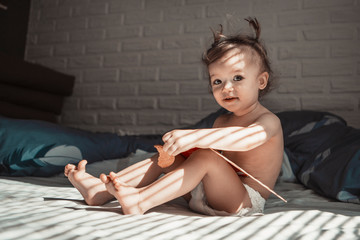 child with tails on his head favors morning in bed in his parents' room on a sunny day. concept of...