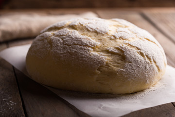 Dough and ingredients for it - eggs flour yeast on brown wooden background. Selective focus.