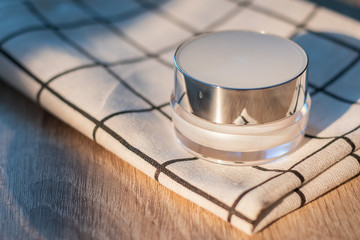 White lotion jar Lotion jars with seeds and flowers around The lotion bottle is placed on the wood.