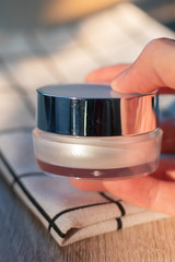 White lotion jar Lotion jars with seeds and flowers around The lotion bottle is placed on the wood.