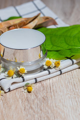 White lotion jar Lotion jars with seeds and flowers around The lotion bottle is placed on the wood.