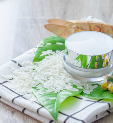 White lotion jar Lotion jars with seeds and flowers around The lotion bottle is placed on the wood.