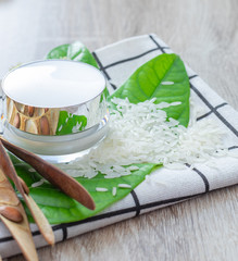 White lotion jar Lotion jars with seeds and flowers around The lotion bottle is placed on the wood.