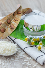 White lotion jar Lotion jars with seeds and flowers around The lotion bottle is placed on the wood.