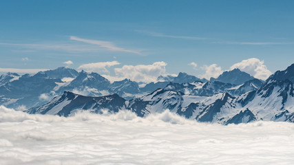 Naklejka premium Switzerland, scenic panoramic view on snow Alps peaks above white clouds