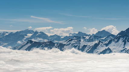 Fototapeta na wymiar Switzerland, scenic panoramic view on snow Alps peaks above white clouds