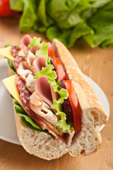 half of long subway baguette sandwich with meat, vegetables and cheese