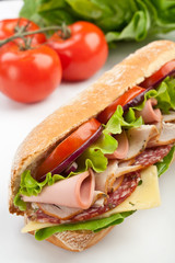 half of long subway baguette sandwich with meat, vegetables and cheese