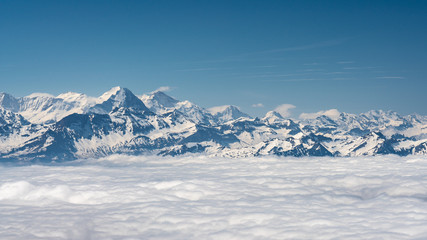 Switzerland, scenic panoramic view on snow Alps peaks above white clouds