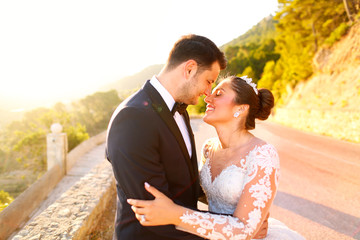 Beautiful wedding couple kissing in the sun near road and trees
